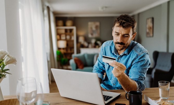 Mężczyzna w jeansowej koszuli sprawdza w internecie, czy jego karta kredytowa może być przeszkodą w zaciągnięciu kredytu hipotecznego