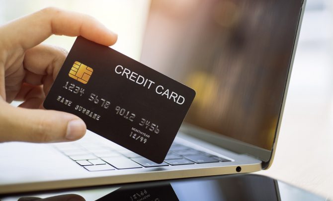 mężczyzna trzymający w dłoni kartę kredytową