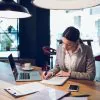 kobieta siedząca przy biurku i wypełniająca wniosek o kredyt konsolidacyjny dla firm.