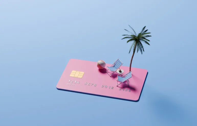 grafika z różową kartą kredytową, palmą, leżakami i piłką plażową na niebieskim tle