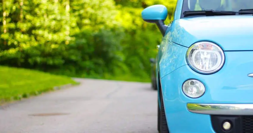 błękitny fiat 500 na tle zielonego lasu