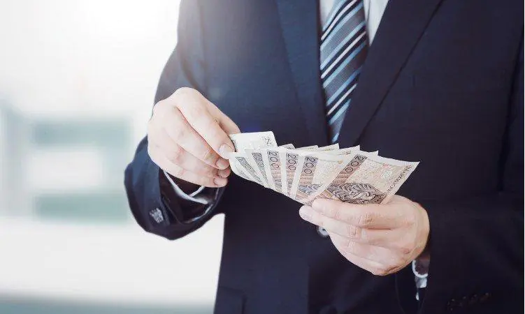 mężczyzna w garniturze z wachlarzem banknotów