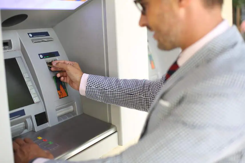 człowiek wypłacający pieniądze z bankomatu
