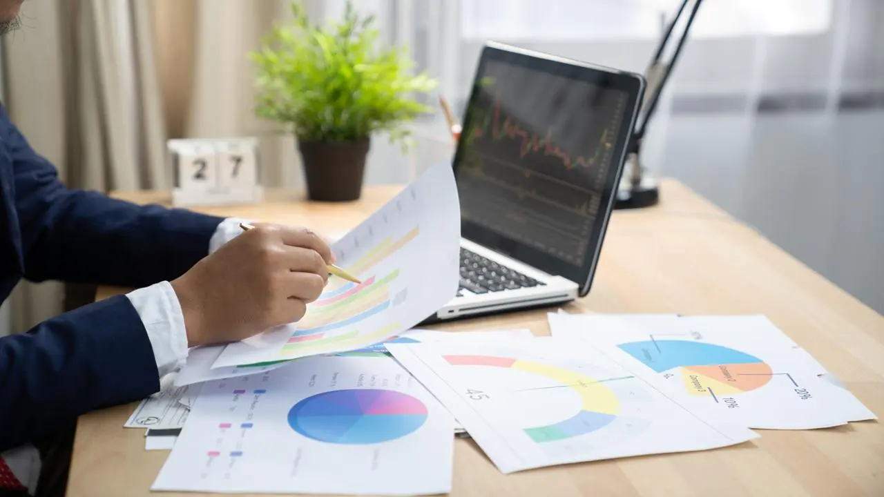 Pracownik banku siedzący przy biurku i analizujący ryzyko kredytowe na podstawie dokumentów.