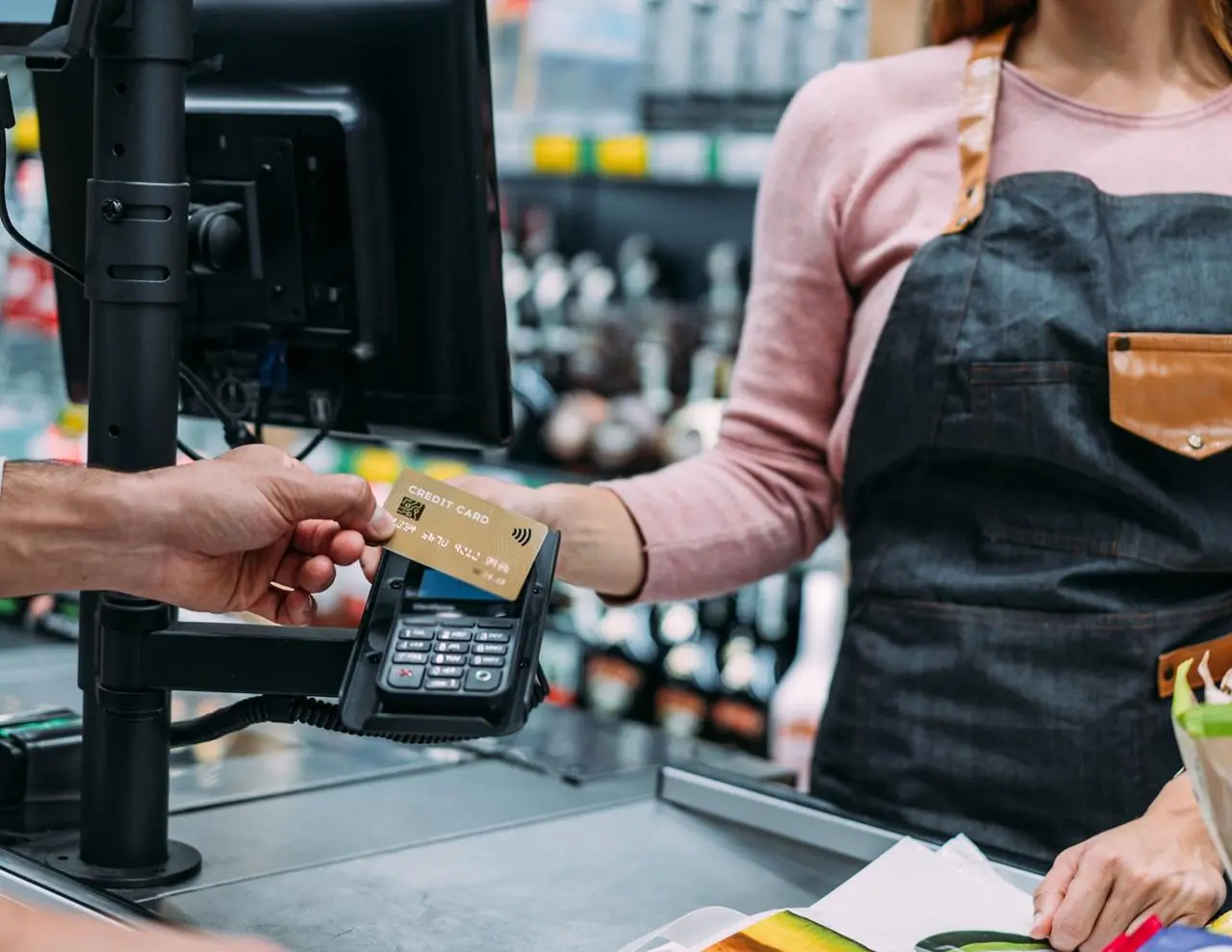 Mężczyzna płacący kartą za zakupu w sklepie spożywczym, który chce skorzystać z usługi cashback