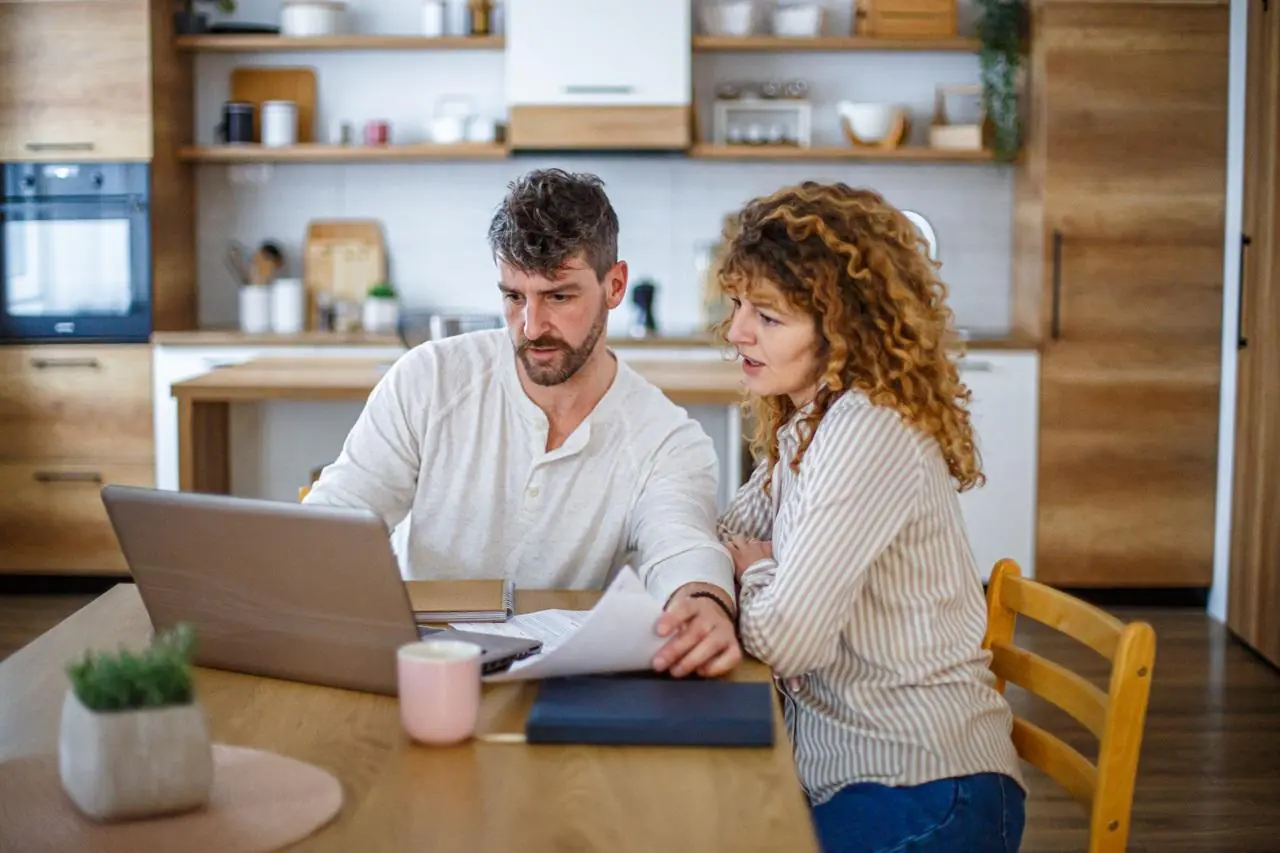 Młode małżeństwo siedzi przy laptopie i sprawdza, gdzie zaciągnąć kredyt konsolidacyjny dla zadłużonych