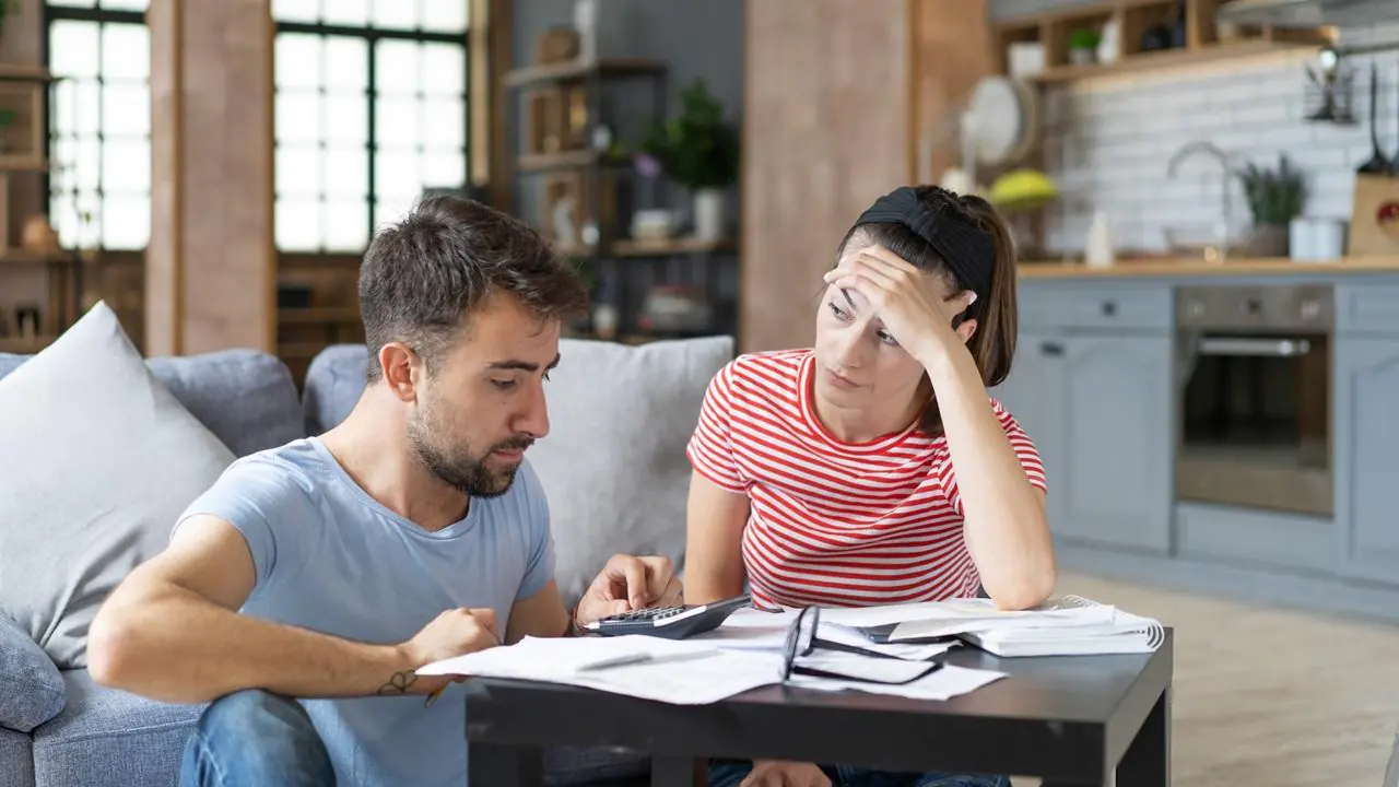 Zmartwione, młode małżeństwo sprawdzające faktury i zastanawiające się nad prolongatą kredytu.
