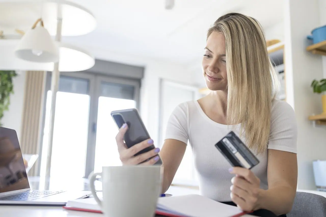 Młoda kobieta sprawdza na telefonie jakie są rodzaje kont osobistych
