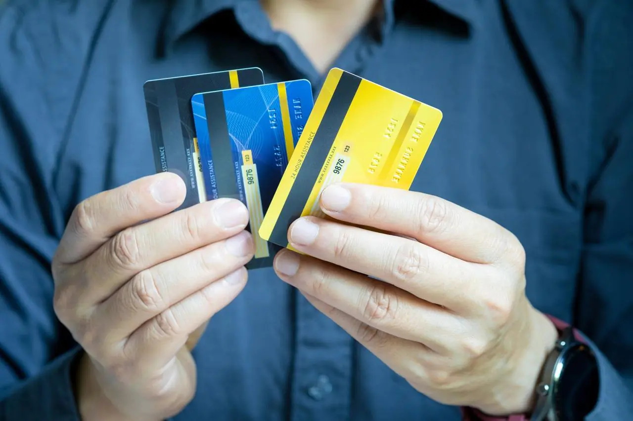 Mężczyzna trzyma w ręku karty przedpłacone, karta prepaid