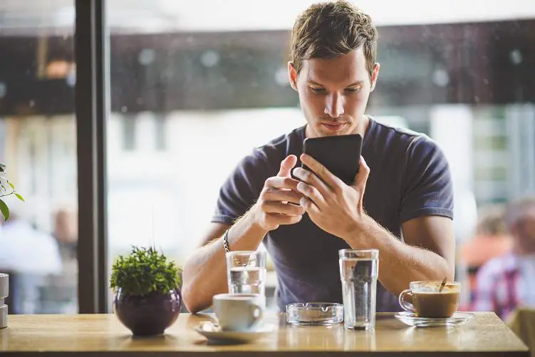 mężczyzna w kawiarni zaciągający przez telefon kredyt na klik online