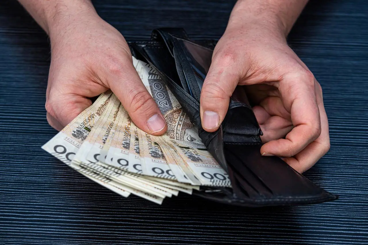 Mężczyzna liczy pieniądze w portfelu, które otrzymał w ramach kredytu 0%