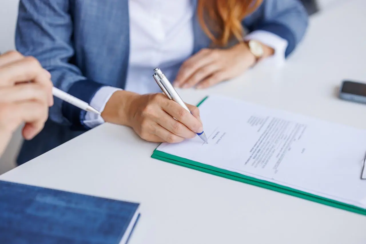 Zbliżenie na dłonie kobiety, która podpisuje umowę kredytową