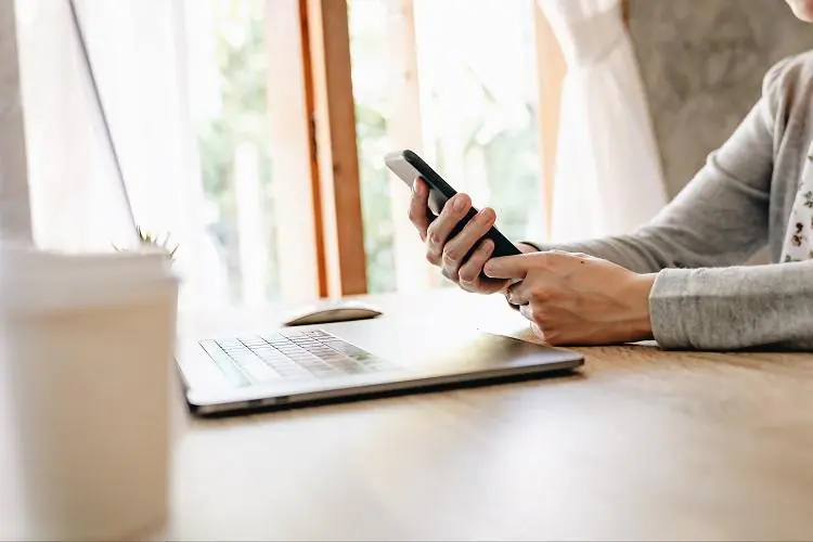 kobieta trzymająca w dłoniach smartfon próbująca zaciągnąć kredyt na telefon