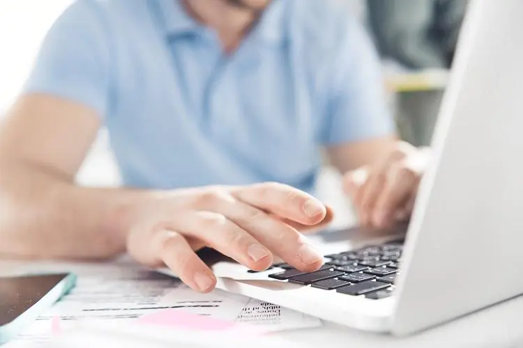 mężczyzna przy laptopie zlecający przelew na konto podatkowe