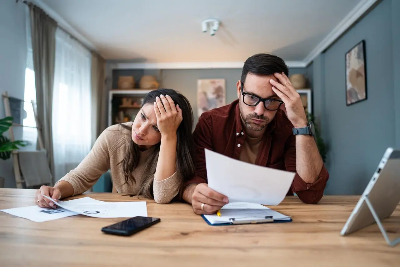 Para młodych ludzi w trakcie rozwodu, czytająca umowy i zastanawiająca się nad podziałem spłaty kredytu gotówkowego