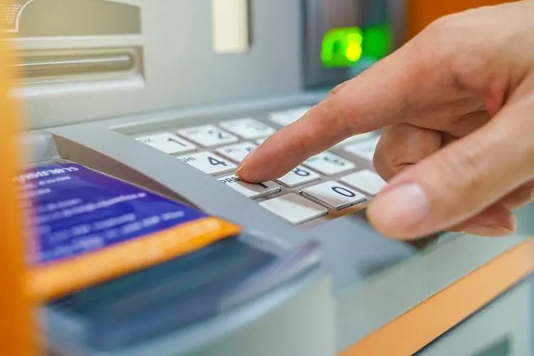 palec wpisujący pin na klawiaturze bankomatu