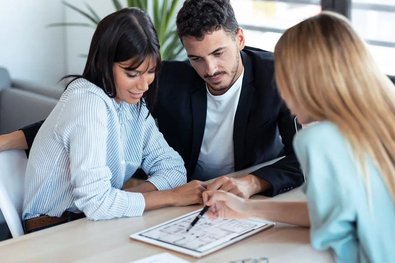 Młoda kobieta podczas spotkania w banku wybiera kredyt hipoteczny z partnerem.
