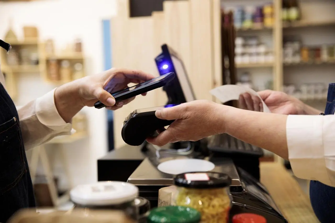 Mężczyzna płaci za zakupy telefonem zbliżeniowo