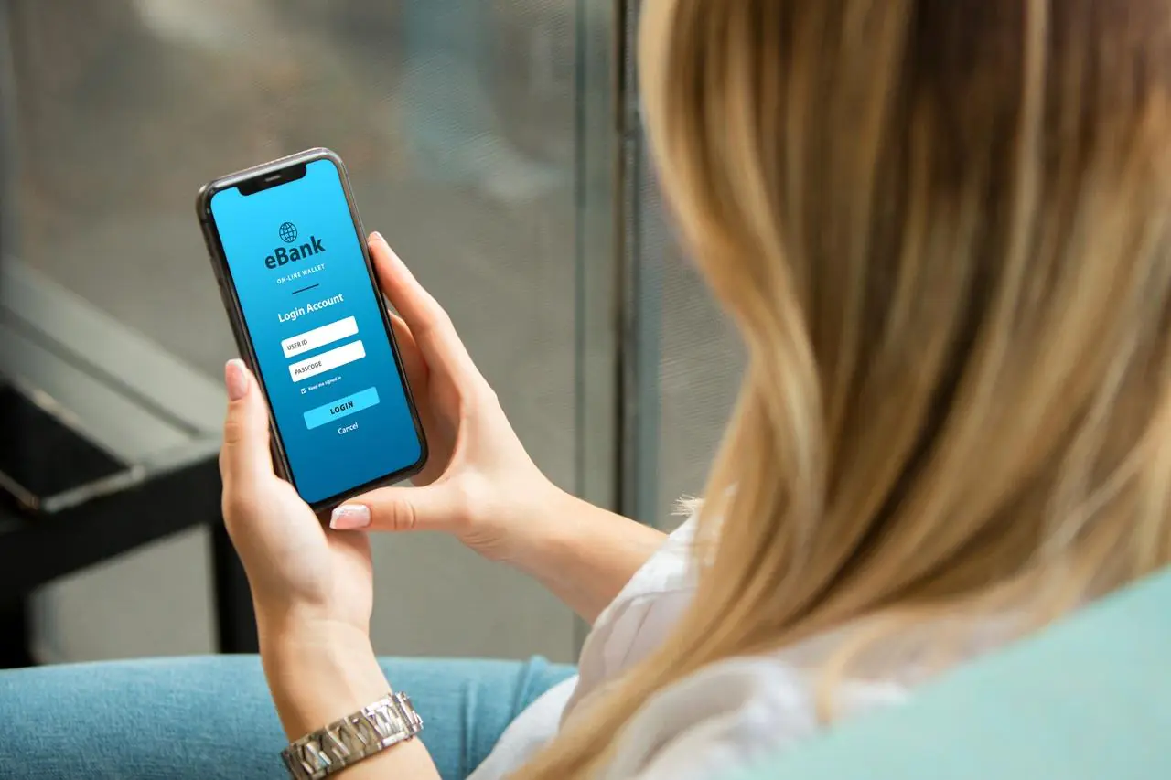 Kobieta loguje sie do banku za pomocą aplikacji mobilnej, żeby zmienić swoje dane