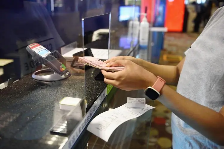kobieta wymieniająca walutę w kantorze i sprawdzająca na ekranie terminala spread walutowy