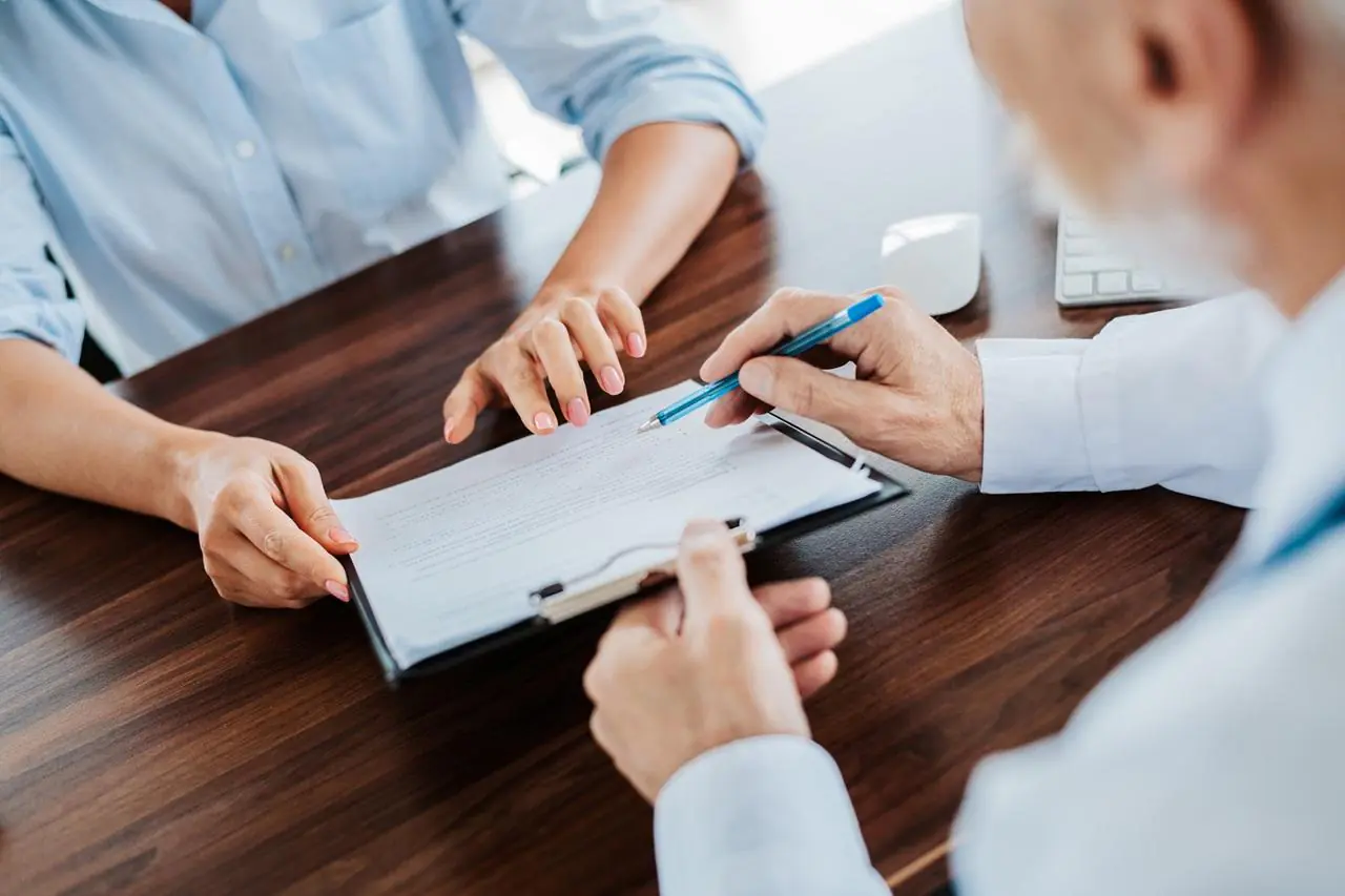 Kobieta podpisuje w banku aneks do umowy o kredyt hipoteczny