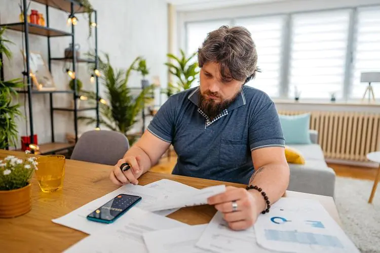 Mężczyzna sprawdza stan swoich finansów - liczy rachunki