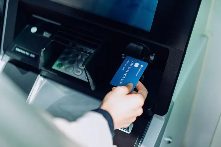 osoba sprawdzająca, jak wypłacić pieniądze z bankomatu