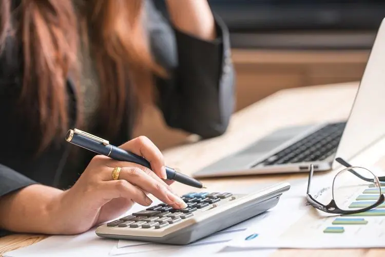 Kobieta liczy na kalkulatorze jaki może wziąć kredyt przy zarobkach 4000 zł netto
