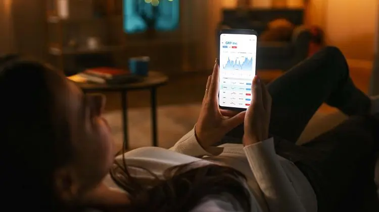 Kobieta leży na kanapie i sprawdza telefonie ile zarabia na lokacie overnight