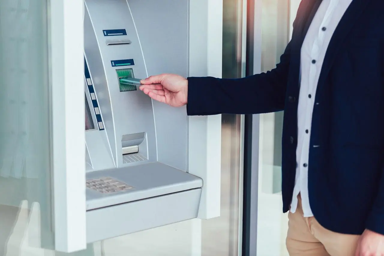 Mężczyzna korzysta z bankomatu za pomocą karty