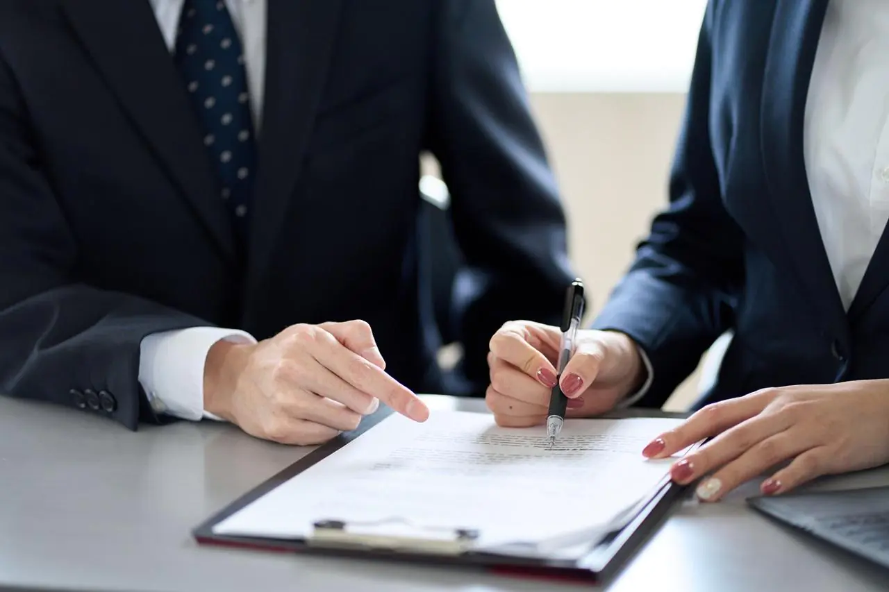Zbliżenie na dłonie dwóch eleganckich osób czytających umowę cesji wierzytelności