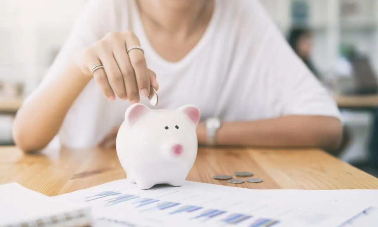kobieta wrzucająca monety do świnki skarbonki