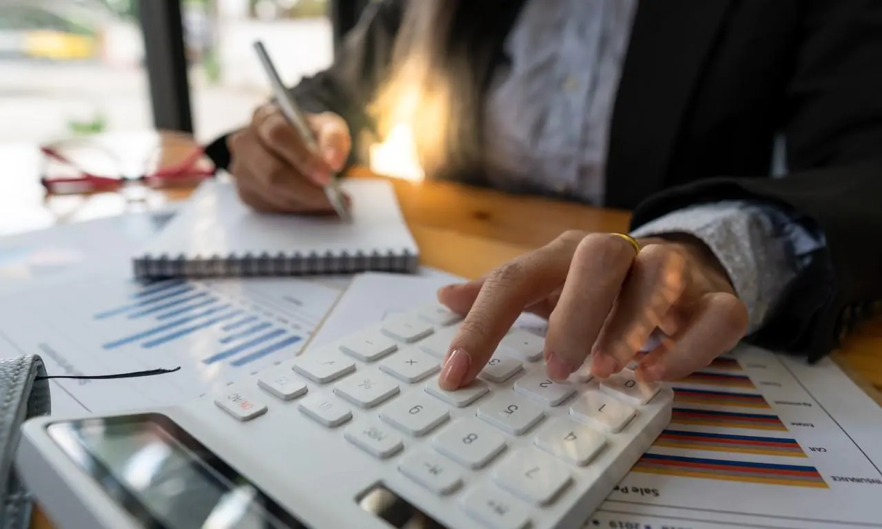 kobieta obliczająca na kalkulatorze, jak deflacja wpływa na jej sytuację finansową