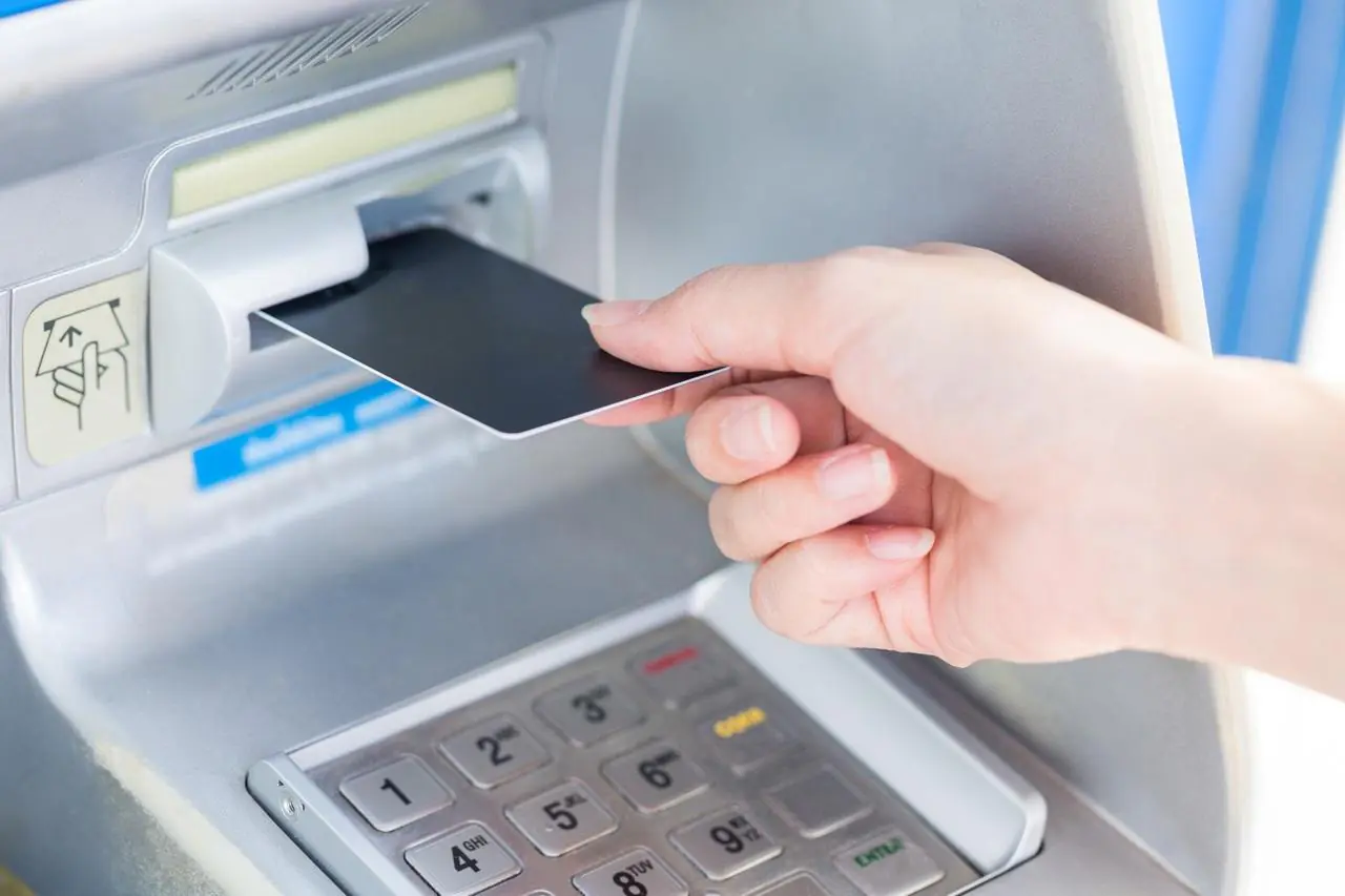 Kobieta wkłada kartę bankomatową do terminala