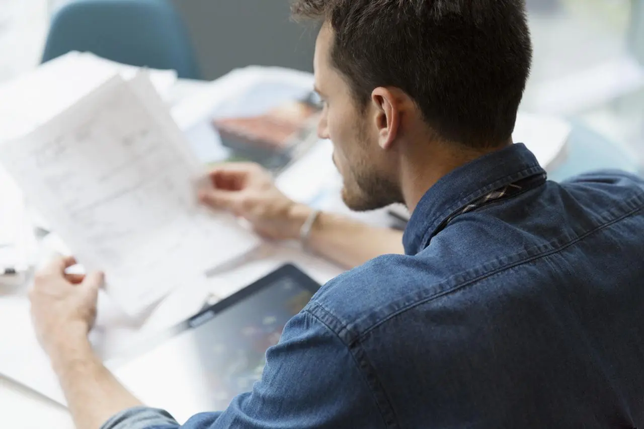 Mężczyzna kompletuje dokumenty potrzebne do zaciągnięcia kredytu gotówkowego