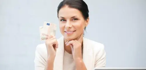 kobieta z banknotem w dłoni siedząca przed laptopem
