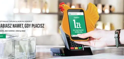dłoń zbliżająca telefon komórkowy do terminala płatniczego