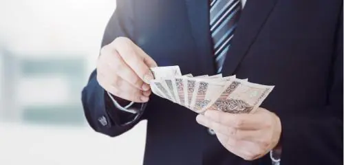 mężczyzna w garniturze z wachlarzem banknotów