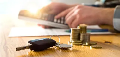 mężczyzna obliczający na kalkulatorze, co się bardziej opłaca - leasing czy kredyt