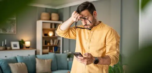mężczyzna w żółtej koszuli, który właśnie otrzymał Alert BIK w postaci wiadomości SMS