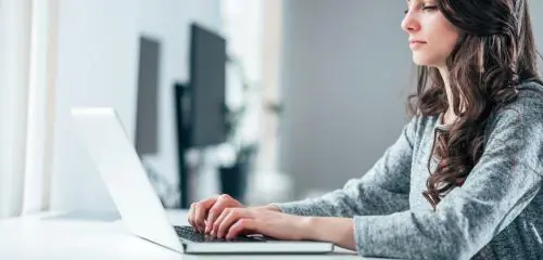 Kobieta robi przelew online za pomocą swojego laptopa