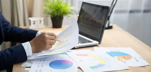 Pracownik banku siedzący przy biurku i analizujący ryzyko kredytowe na podstawie dokumentów.