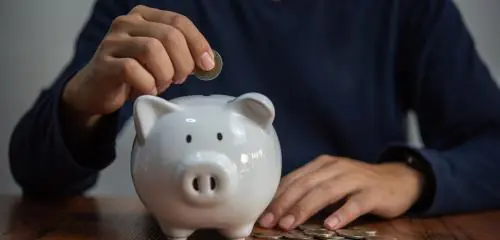 Kobieta wrzuca monety do świnki-skarbonki