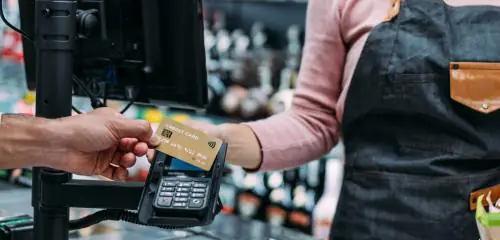 Mężczyzna płacący kartą za zakupu w sklepie spożywczym, który chce skorzystać z usługi cashback