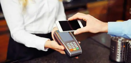mężczyzna przykładający telefon do terminala