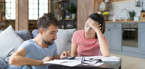 Zmartwione, młode małżeństwo sprawdzające faktury i zastanawiające się nad prolongatą kredytu.