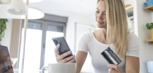 Młoda kobieta sprawdza na telefonie jakie są rodzaje kont osobistych