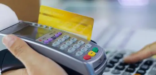 Klient płaci kartą debetową wsuniętą do terminala.