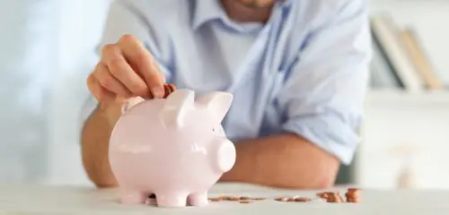 mężczyzna wrzucający monetę do skarbonki
