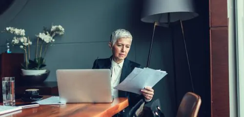 Starsza pani biznesmen siedzi w biurze i sprawdza, ile kosztuje akredytywa bankowa.